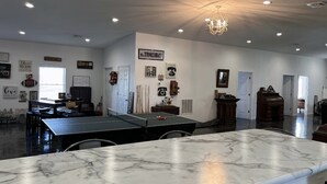 A spacious room with a ping pong table, a marble countertop, and various wall decorations including a 'Bless This Home' sign. - Private country getaway in the middle of nowhere! (Newtown)