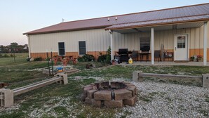 A single-story building with a covered porch, a fire pit, and a barbecue area. - Private country getaway in the middle of nowhere! (Newtown)