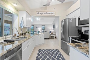A modern kitchen with white cabinetry, stainless steel appliances, and a granite countertop. - Pet-Friendly Heated Pool Home | 4BR, Fenced Yard, Ping Pong & Bikes | SW Cape Coral | Sleeps 11 (Cape Coral)