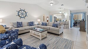 Un salon spacieux avec un grand canapé, une table basse et une roue décorative accrochée au mur.