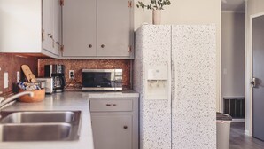 A modern kitchen with grey cabinets, a speckled refrigerator, a microwave, and a coffee maker. - 2 Bedroom Home less than 2 miles to Jacks Fork River (Eminence)