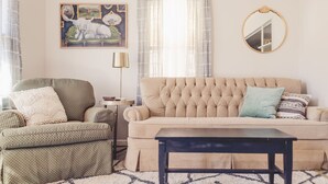 A living room with a beige sofa, a green armchair, a small side table, a floor lamp, and a mirror on the wall. - 2 Bedroom Home less than 2 miles to Jacks Fork River (Eminence)
