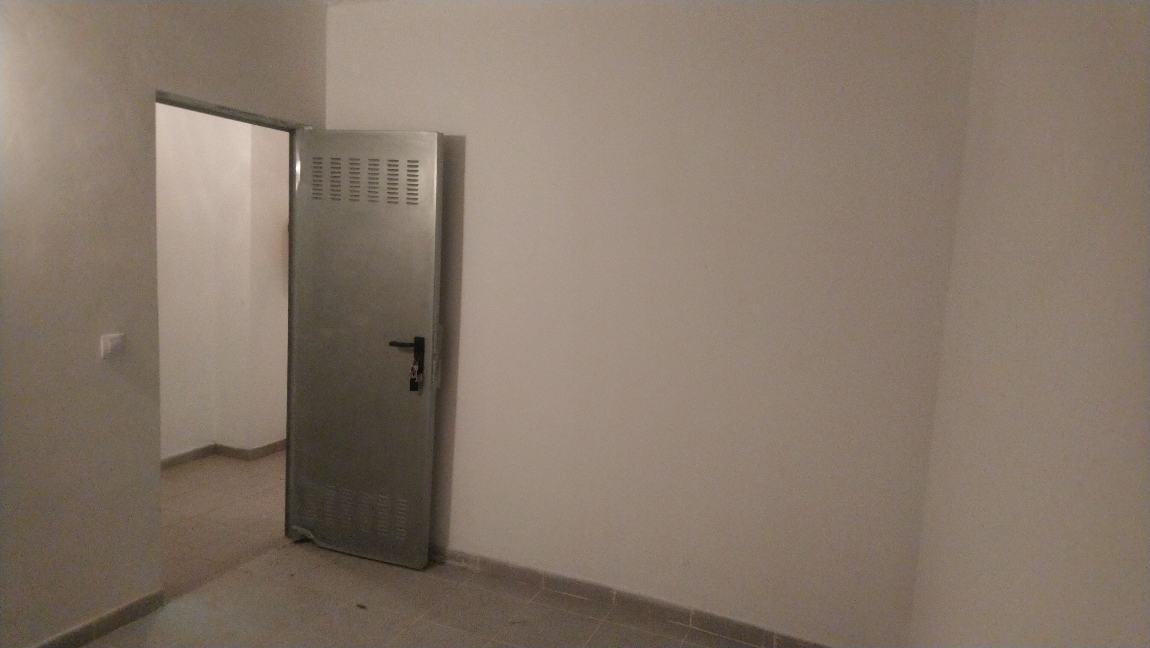 A narrow hallway with a door that has a keyhole and a handle.