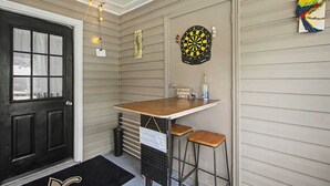 Eine Barbereich mit einer Dartscheibe, zwei Barhocker und einem kleinen Tisch.