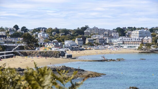 Une ville côtière dotée d’une plage de sable, d’une côte rocheuse et de bâtiments situés le long du rivage.