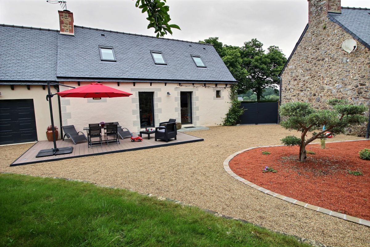 A house with a patio area featuring outdoor furniture and a red umbrella.