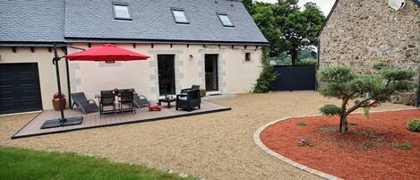 A house with a patio area featuring outdoor furniture and a red umbrella.