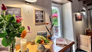 Une pièce chaleureuse avec une table en bois, un vase rempli de fleurs, une bougie et des panneaux décoratifs encadrés accrochés au mur.