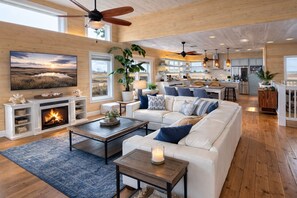 A spacious living room with a fireplace, a large TV, and a cozy seating area. - Port Aransas Large Luxury Beach House w/ Private Pool and Golf Cart Boardwalk (Port Aransas)