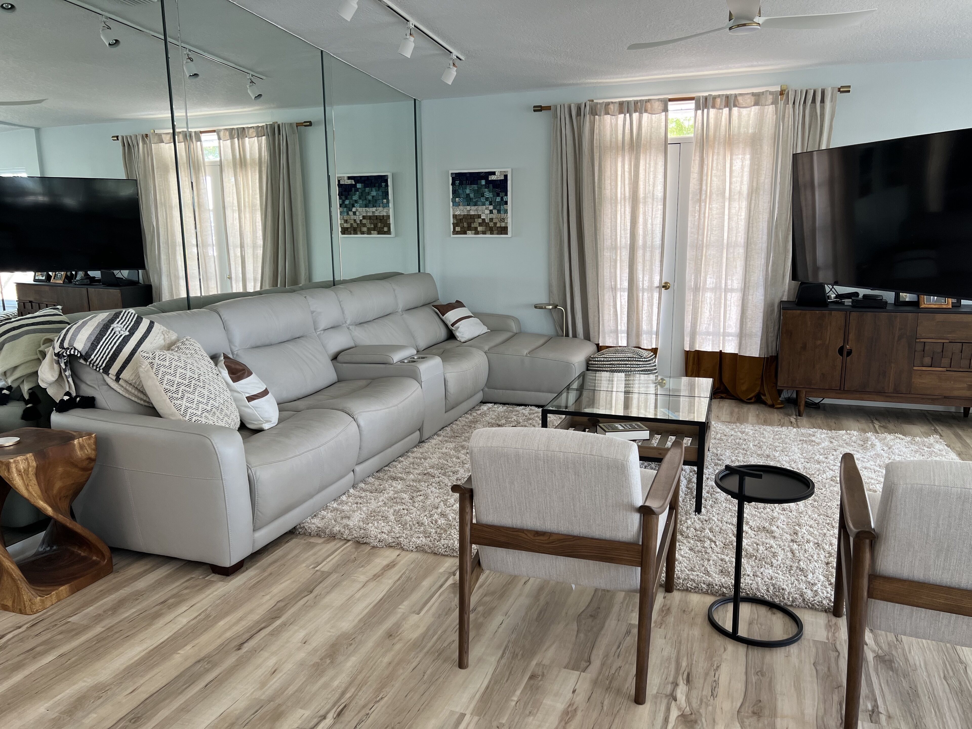 A modern living room with a sectional sofa, a glass coffee table, and a TV.