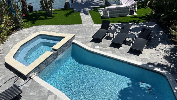A swimming pool with a hot tub, surrounded by lounge chairs and a covered seating area. - Waterfront Renovated Luxury Home with pool and spa - 5 min walk to the beach (Indian Rocks Beach)