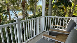 A covered outdoor seating area with white railings, wooden benches, and grey cushions. - Waterfront Renovated Luxury Home with pool and spa - 5 min walk to the beach (Indian Rocks Beach)