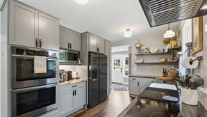 Una cocina moderna con electrodomésticos de acero inoxidable, armarios grises y encimera negra.