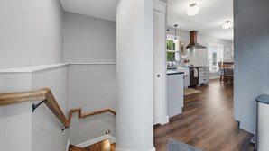 Una cocina moderna con armarios blancos, una isla de madera y un comedor con mesa y sillas.