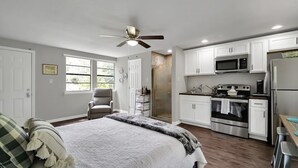 Une chambre à coucher avec un lit, une chaise, un ventilateur de plafond et une fenêtre.