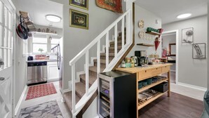 Une cuisine moderne dotée d’un four encastré, d’une table à manger en bois avec de la vaisselle, et d’un escalier menant à un autre niveau.