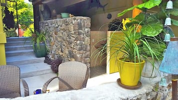 Relax in the serene outdoor seating area with wicker chairs and a lush potted plant.