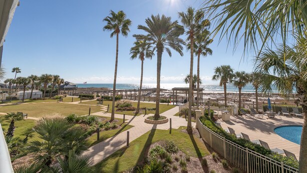 A resort with a pool, palm trees, and a view of the beach. - Upscale Family-Friendly Beachfront Condo Conveniently Located (Gulf Shores)
