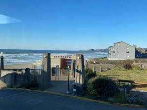 A beach entrance with a sign reading "Newport Beach" and a building in the background.