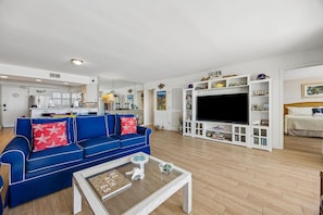 Un salon moderne avec un canapé bleu, une table basse et un téléviseur.
