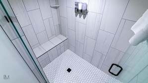 Een moderne douche met witte tegels en een vloerpatroon van hexagons.