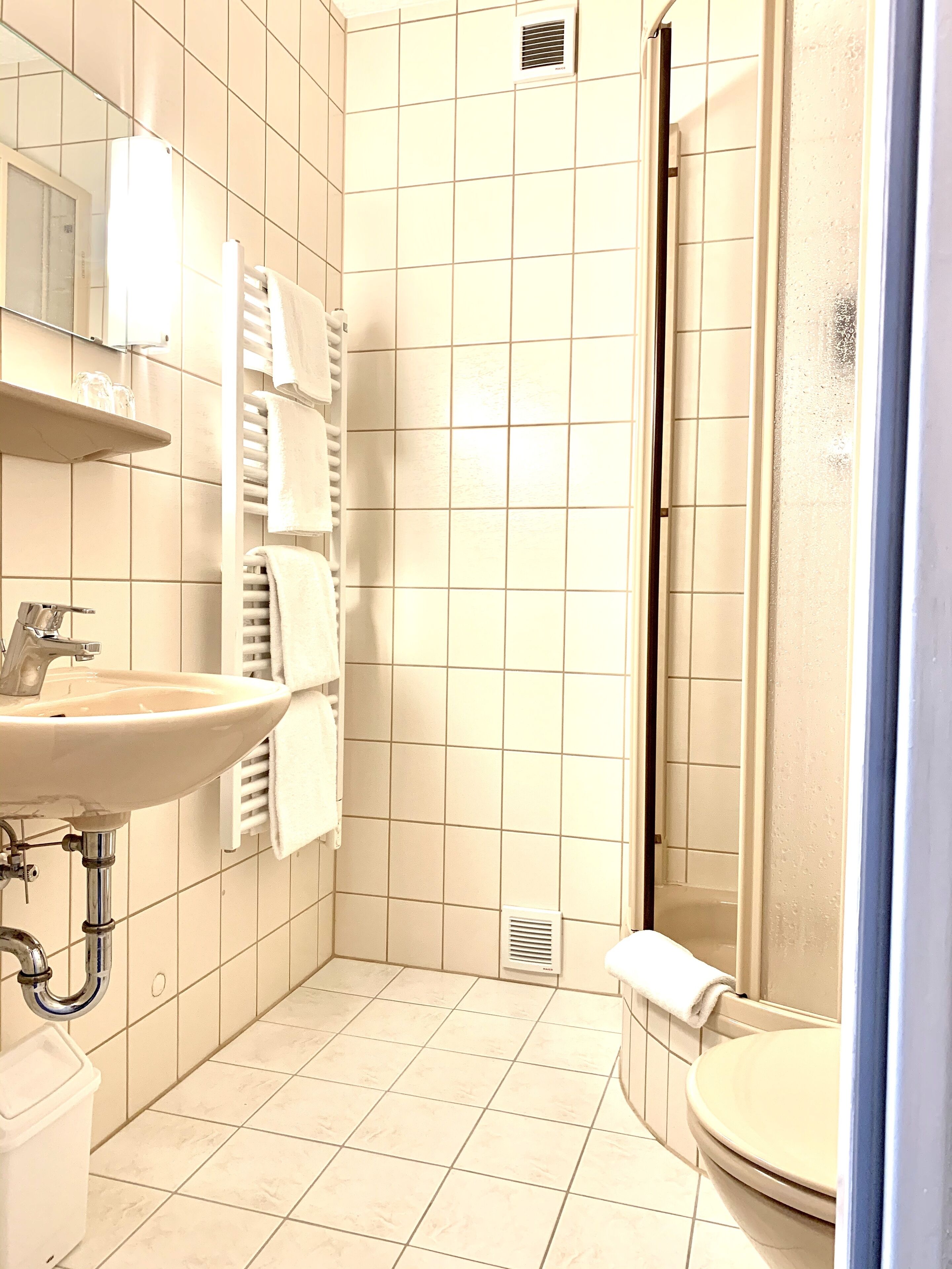 Un bagno con lavandino, specchio, asciugamano e water.