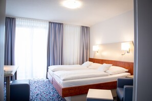 Une chambre d’hôtel avec un grand lit, un bureau, une chaise et une table de chevet.
