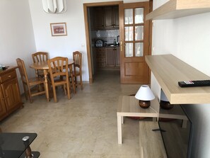 Une cuisine de taille réduite, dotée de meubles en bois et d’un coin repas avec une table et des chaises.