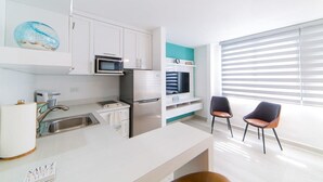 Eine moderne Küche mit weißen Schränken, Edelstahlgeräten und einem Fenster mit Jalousien.