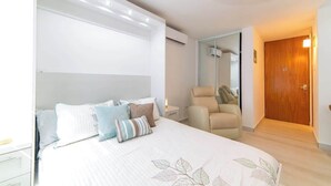 Ein Schlafzimmer mit Bett, Stuhl, Holztür und Spiegel.
