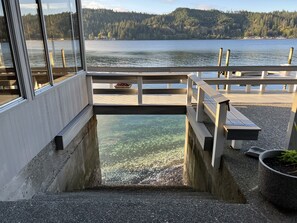 A dock with a concrete platform leading to a body of water, surrounded by a forested hillside.