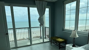 Un dormitorio con vista a la playa, una banca, una lámpara y una cama.