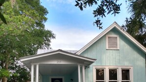 Uma casa azul clara com varanda e o número 214 na fachada.