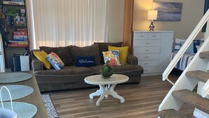 Una sala de estar con sofá, mesa de centro y escalera.