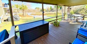 A covered outdoor deck with a built-in bench, a table, and chairs. - Pier Serenity Waterfront! (Huntsville)