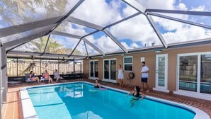 A covered swimming pool with a clear blue water, surrounded by a brick patio and a metal roof structure. - Pool + Game Room 4BR · Cheerful Hollywood Getaway (Hollywood)
