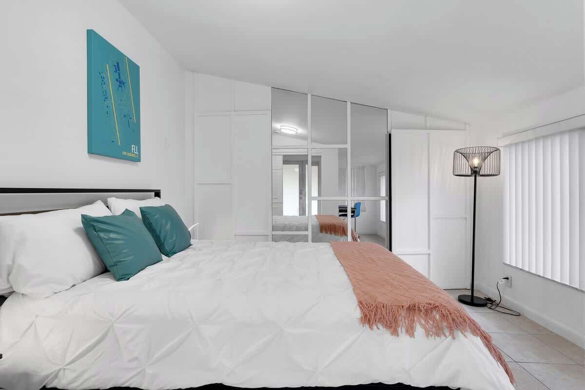 Ein modernes Schlafzimmer mit Bett, Stehlampe und Spiegel.