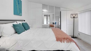 A modern bedroom with a bed, a floor lamp, and a mirror. - Pool + Game Room 4BR · Cheerful Hollywood Getaway (Hollywood)