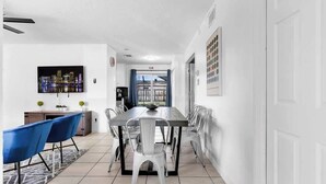 A modern dining area with a long table, blue and white chairs, and a cityscape painting on the wall. - Pool + Game Room 4BR · Cheerful Hollywood Getaway (Hollywood)