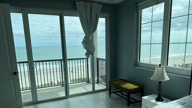 Ein Schlafzimmer mit Blick auf den Strand, eine Bank, eine Lampe und ein Bett.