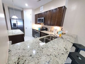 A kitchen with granite countertops, stainless steel appliances, and dark wooden cabinets. - Gone Coastal 3 BR Direct Oceanfront  (Myrtle Beach)