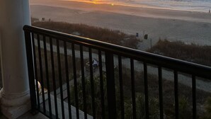 Un coucher de soleil sur l’océan, vu depuis un balcon doté d’une balustrade.