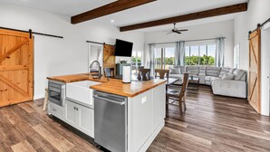 Un vaste espace de vie comprenant un îlot de cuisine, un plancher en bois et une grande fenêtre offrant une vue dégagée.