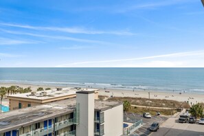 Vista de una playa con un estacionamiento y edificios en primer plano.