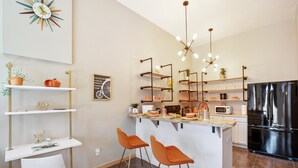 Una cucina moderna con isola centrale, sgabelli da bar, frigorifero e diversi elettrodomestici.