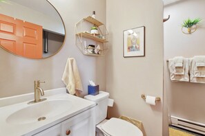 A bathroom with a white sink, a toilet, a towel rack, and a mirror. - Page 1-Mid-Century Modern With Mountain View (Victor)