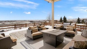 Eine Terrasse im Freien mit Korbmöbeln und Blick auf eine verschneite Landschaft.