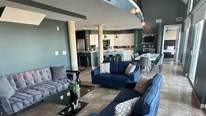 Un amplio espacio de sala con una escalera curva, muebles modernos y una cocina al fondo.