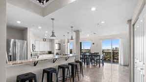 Una cocina moderna con una isla central, taburetes de bar y vistas de la ciudad a través de amplios ventanales.
