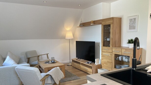 Een moderne woonkamer met een bank, televisie en houten kasten.